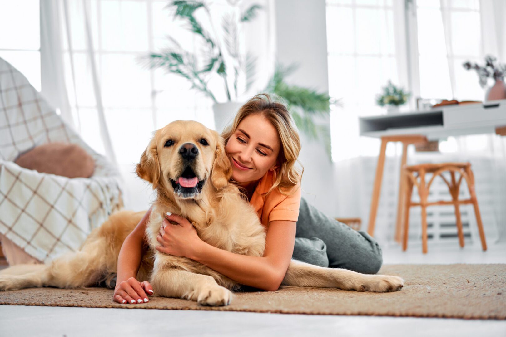 Woman happily hugging her golden retriever indoors.